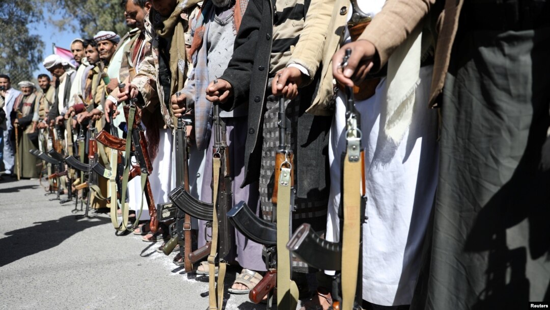 FILE - Houthi backers hold weapons during a protest outside the U.S. Embassy in Sanaa, Yemen, Jan. 18, 2021. 