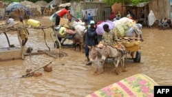 Local residents carry their belongings as they evacuate their homes in Niamey, the capital of Niger, on August 19, 2012. 