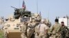 FILE - Kurdish fighters from the People's Protection Units (YPG) chat with members of U.S. forces in the town of Darbasiya next to the Turkish border, Syria, April 29, 2017.