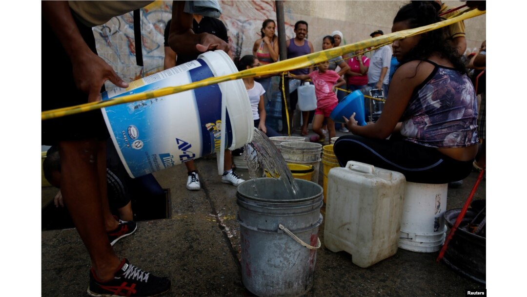 Locals queue to collect water from an underground water main pipeline in Caracas, Venezuela, April 1, 2019.