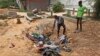 Afrah Ibrahim, center, searches through the clothes of the dead lying in a hole, to try and find the clothes last worn by his missing sister, without success, outside a hospital in Mogadishu, Somalia, Oct. 17, 2017. 
