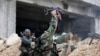FILE - Syrian soldiers fire their weapons during a battle with rebel fighters at the Ramouseh front line, east of Aleppo, Syria, Dec. 5, 2016.