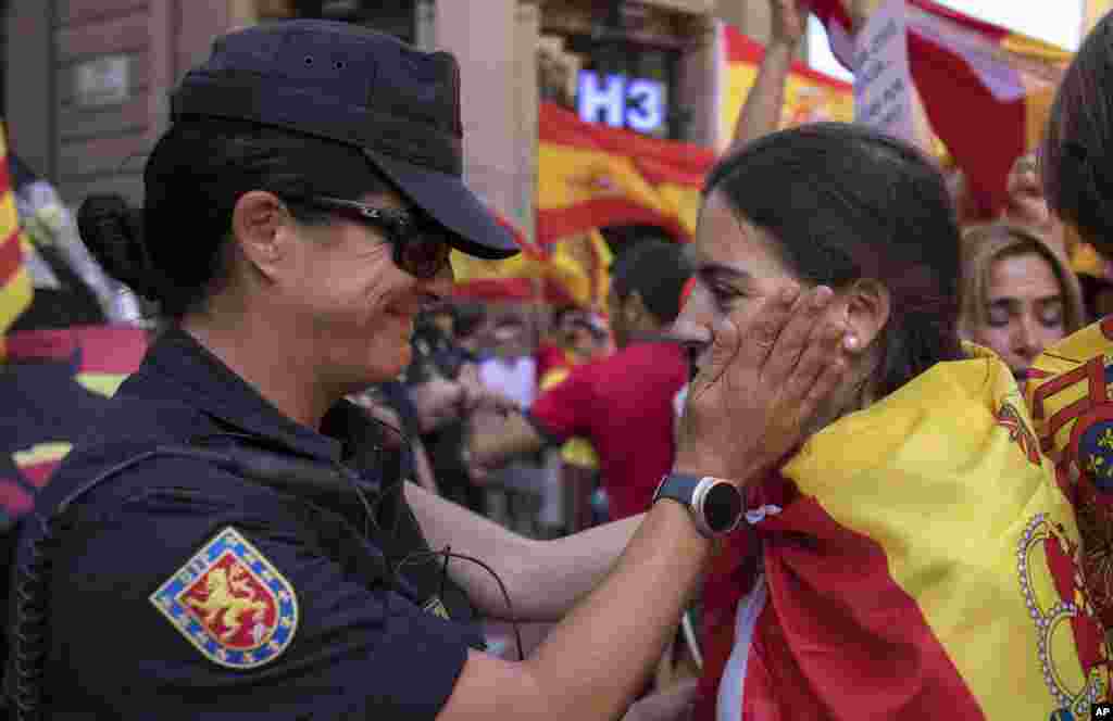 A Spanish police officer speaks with a demonstrator during a protest against the Catalan government's push for secession from the rest of Spain in downtown Barcelona, Spain.
