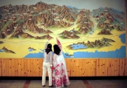 FILE - People point to a map on a wall in Mount Kumgang resort in Kumgang, Sept. 1, 2011.
