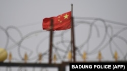 资料照：新疆喀什南部地区一处围着铁丝网的小区里飘扬着中国国旗。 （2019年6月4日）
