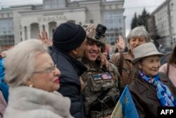 Чоловік обіймає українського солдата, коли радісні херсонці з прапорами України вітали українських військових, які повернули місто під контроль Києва, 13 листопада 2022 року. (Photo by Bulent KILIC / AFP)