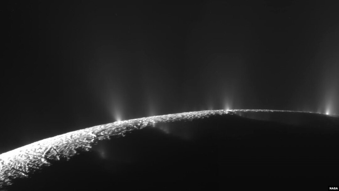 Numerous plumes are seen rising from long tiger-stripe canyons across Enceladus' craggy surface. 