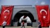 FILE - Men walk at the Galata bridge past two Turkish flags, in Istanbul, Aug. 2, 2016. U.S. and Turkish diplomats are undertaking a complicated effort to improve relations between the two countries.