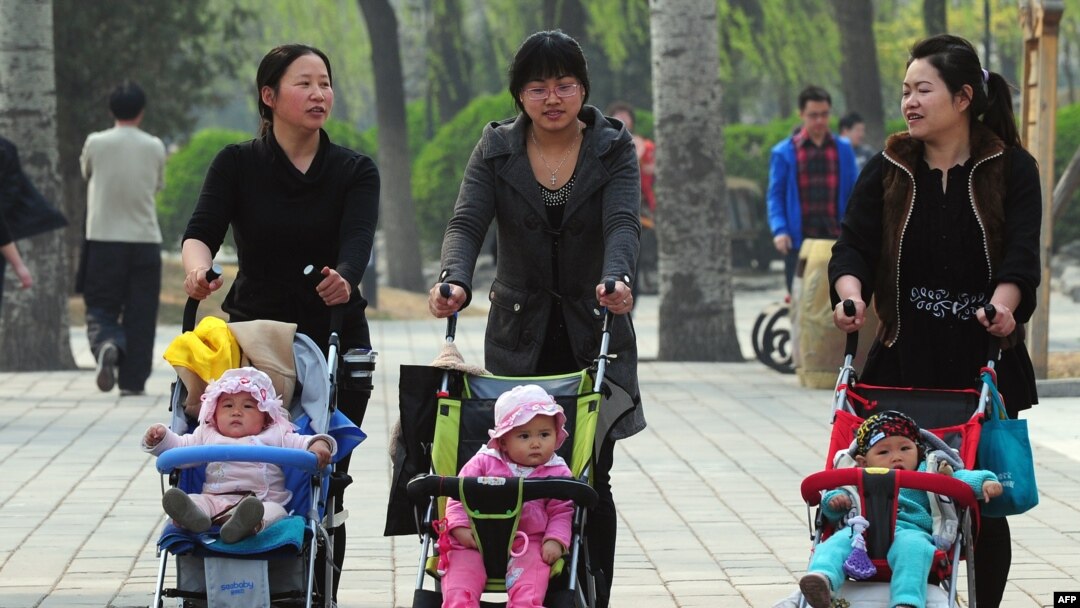 FILE - Women push babies in strollers through a Beijing park during a public holiday.