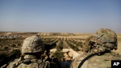 FILE - American troops look out toward the border with Turkey from a small outpost near the town of Manbij, northern Syria, Feb. 7, 2018. 
