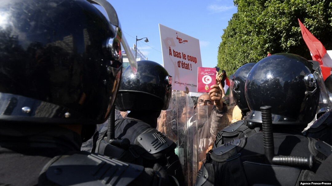 FILE - Protesters confront riot police during an anti-government rally along Habib Bourguiba avenue in Tunisia's capital Tunis, Oct. 10, 2021.