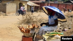A woman roasts maize by the road side along Manchock road, in Kaura Local Government Kaduna State, Nigeria, March 21, 2014.