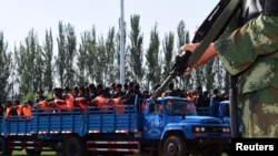 2014年5月27日，新疆伊犁武装警察正在把一批犯罪嫌疑人押送到群众大会上公审判决。