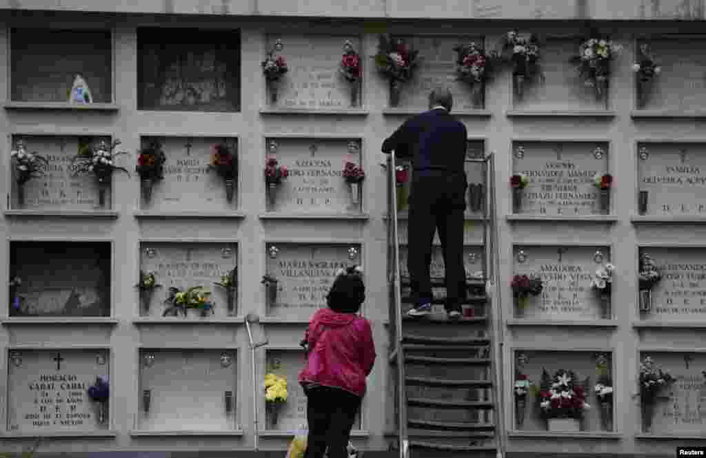 People place flowers in tombs at the municipal cemetery of San Salvador in Oviedo, northern Spain, Oct. 30, 2017.