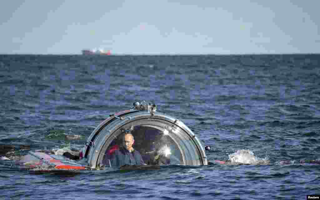 Russia's President Vladimir Putin (L) is seen through the glass of C-Explorer 5 submersible after a dive to see the remains of the naval frigate "Oleg",; which sank in the 19th century, in the Gulf of Finland in the Baltic Sea.
