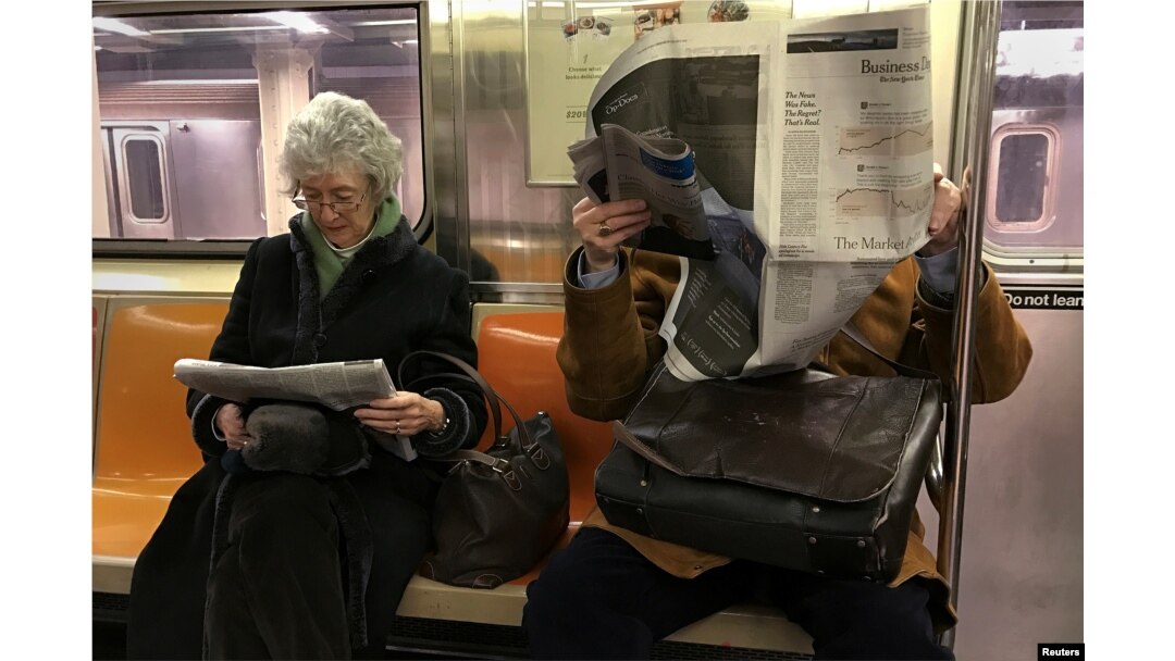 People ride the subway as they read newspapers as the train pulls into the Times Square in Manhattan, New York, Feb. 17, 2017.