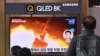 FILE - People watch a television screen showing a news broadcast with file footage of a North Korean missile test, at a railway station in Seoul on Jan. 25, 2022.