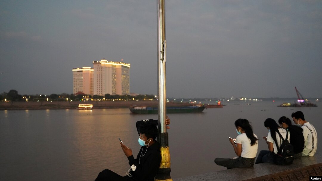 FILE - People uses their mobile phones on the Tonle Sap riverside in Phnom Penh, Cambodia, Feb. 18, 2021.