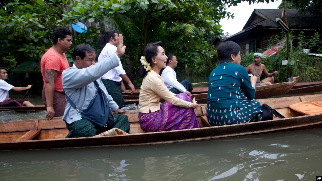 Myanmar opposition leader Aung San Suu Kyi, center, rides a boat on her way to a monastery where flood victims are sheltered, Aug. 3, 2015, in Bago, 80 kilometers (50 miles) northeast of Yangon, Myanmar.