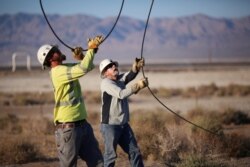 Workers repair lines that were broken during a powerful earthquake that struck Southern California, near the epicenter, northeast of the city of Ridgecrest, July 5, 2019.
