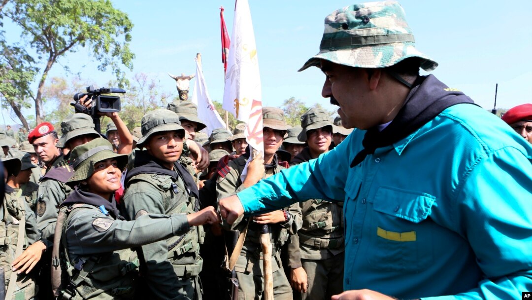 In this handout photo released by Miraflores Press Office, Venezuela's President Nicolas Maduro fist bumps with a cadet at the G/J José Laurencio Silva military training center in the state of Cojedes, Venezuela, May 4, 2019.