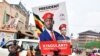 A supporter of Ugandan opposition Presidential candidate Robert Kyagulanyi also known as Bobi Wine, carry his electoral campaign poster ahead of the presidential and parliamentary elections, in Kampala, Uganda, Jan. 12, 2021.