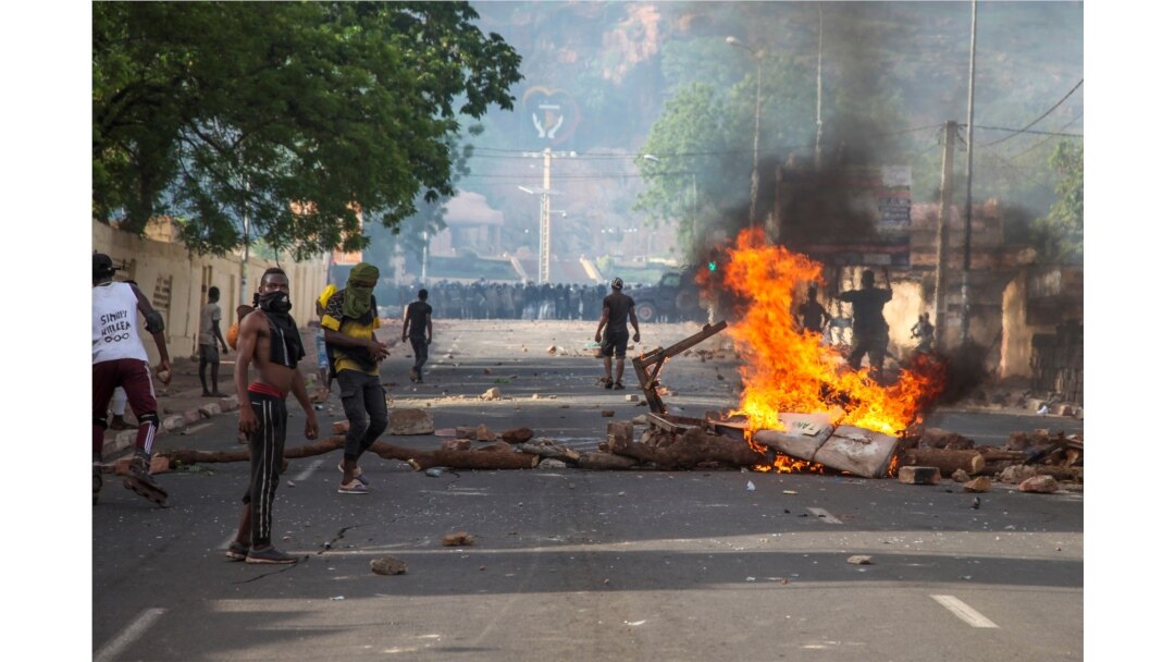 FILE - Protesters demanding President Ibrahim Boubacar Keita's resignation stand by a burning roadblock in the capital Bamako, Mali, June 19, 2020.