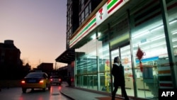 一名女子走過北京街頭一家7-Eleven便利店。（2012年1月3日）
