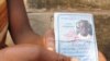 A mother shows the identification of her son who was killed in one of the many recent pro-democracy protests in Guinea.