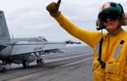 FILE - A U.S. fighter jet takes off from the U.S. aircraft carrier USS Ronald Reagan to patrol the international waters off the South China Sea, Aug. 6, 2019.