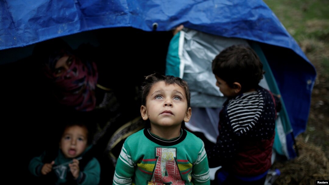 FILE PHOTO: A Syrian refugee boy stands in front of his family tent at a makeshift camp for refugees and migrants next to the Moria camp on the island of Lesbos, Greece, Nov. 30, 2017.