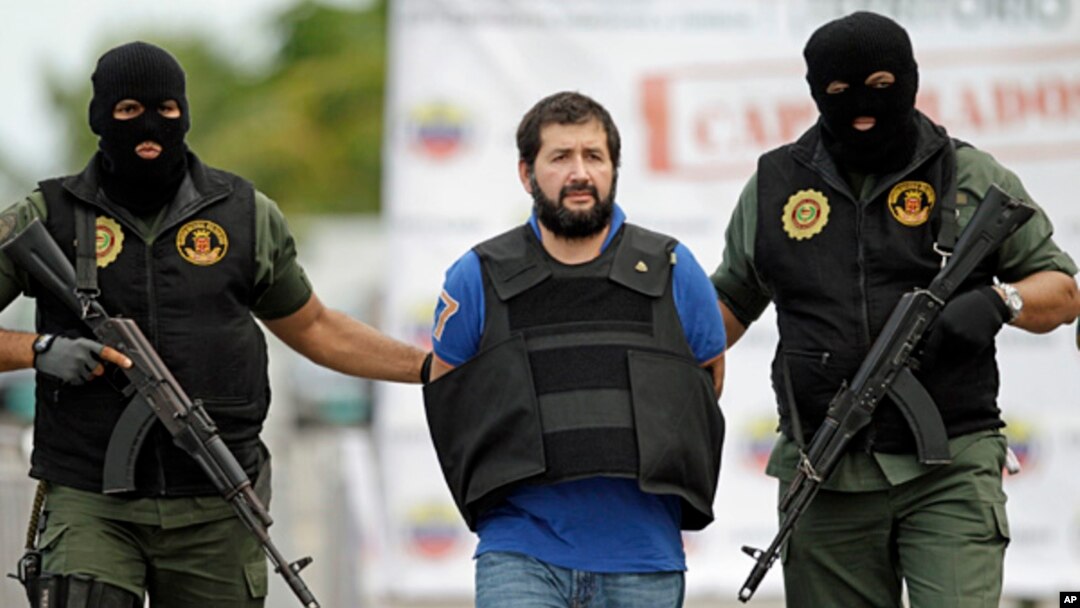 FILE - Daniel Barrera , one of Colombia's most wanted drug lords, whose alias is “El Loco” is escorted in a flak jacket by National Guard troopers as he is deported to Colombia from Venezuela, Nov. 14, 2012.