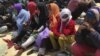 FILE - Migrants who attempted to sail to Europe sit on the shore after their boat was intercepted at sea by the Libyan coast guard in Khoms, Libya, May 6, 2015.
