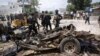 Somali soldiers stand near the wreckage of a car used in a suicide car bomb attack outside the Criminal Investigation Department (CID) in Mogadishu, Somalia, July 31, 2016.