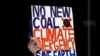 An environmental activist from Extinction Rebellion holds up a placard during a protest against the India-backed Adani coal mine project, outside the GHD engineering office building in Sydney, Aug. 13, 2019. - Scores of environment advocates occupied…