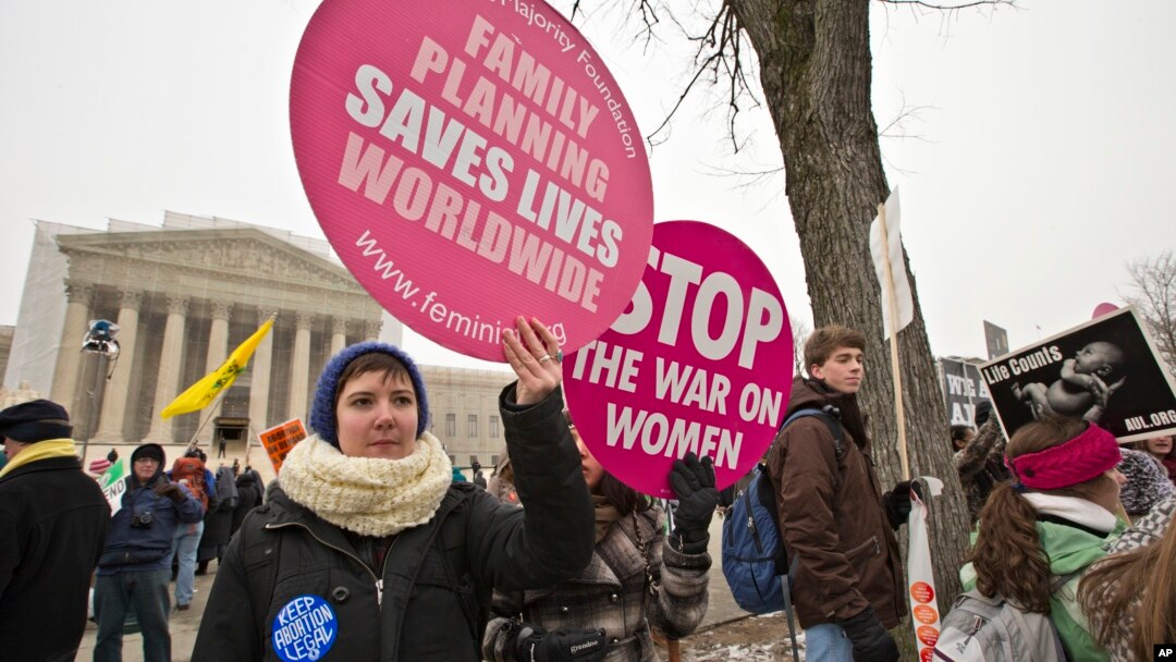 Abortion rights protesters hold signs as anti-abortion activists march past the Capitol to the Supreme Court in Washington, Jan. 25, 2013.