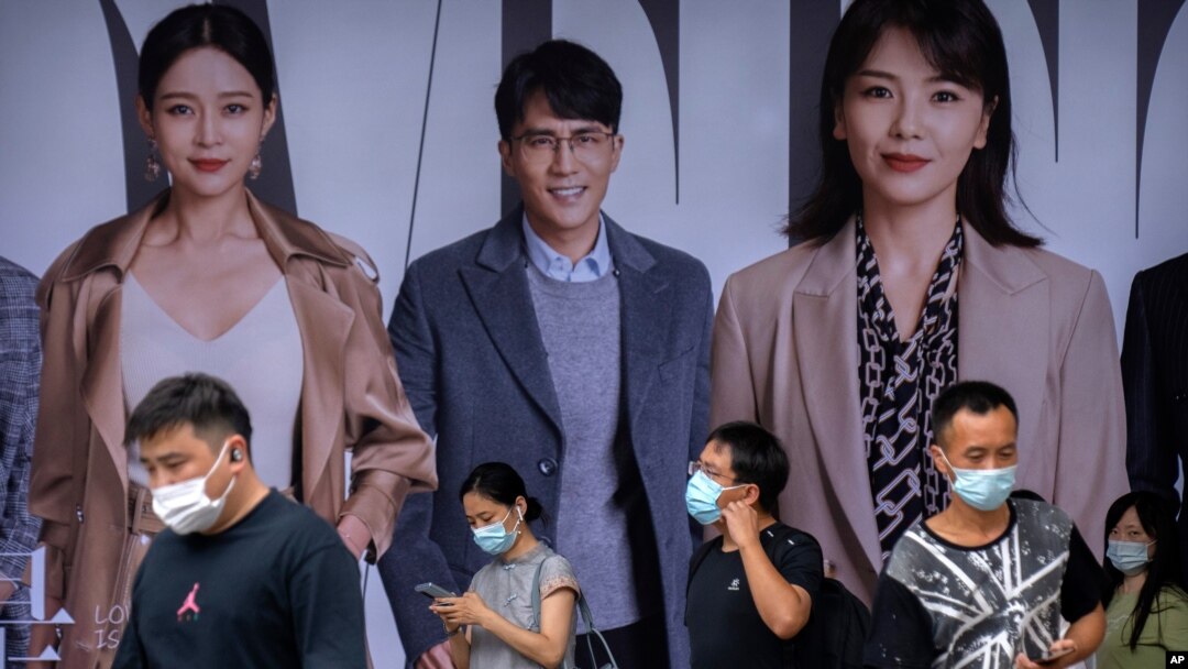 4일 중국 베이징의 전철역 광고판 앞에서 마스크를 쓴 출근길 시민들.