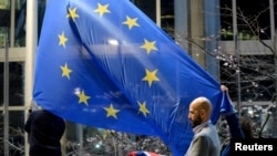 Workers replace the British flag outside the European Parliament building with the European Union flag, in Brussels, Belgium, Jan. 31, 2020