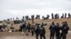 Turkish police stand by migrants camping in Edirne near the Turkish-Greek border, March 5, 2020. 
