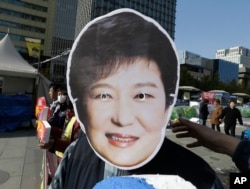 FILE - A South Korean protester wears a mask of South Korean President Park Geun-hye during a rally calling for Park to step down in downtown Seoul, South Korea, Nov. 11, 2016. Tens of thousands of South Koreans are expected to march in Seoul to demand Park's re