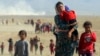 Displaced Yazidis, fleeing violence from forces loyal to the Islamic State group, head toward the Syrian border Aug. 11, 2014.