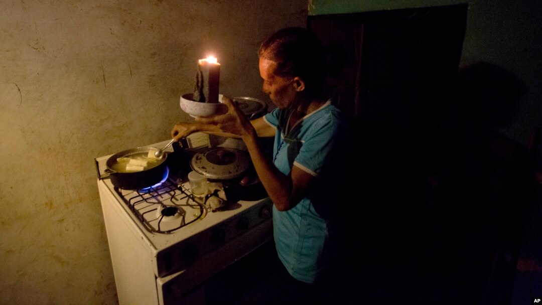 Mireya Marquez uses candlelight to cook her dinner of boiled "cassava," also known as yuca and manioc, Aug. 19, 2018, during a blackout in Maracaibo, Venezuela. For months Maracaibo's residents have endured rolling blackouts, but things turned dire Aug. 10 when a fire destroyed a main power line supplying the city of 1.5 million people.