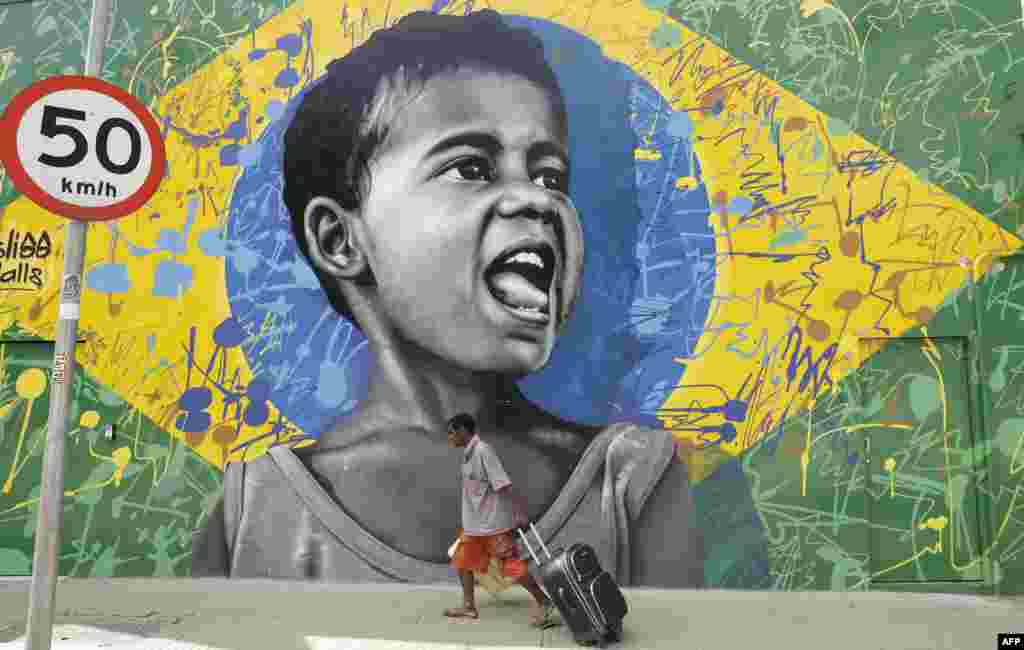 A man walks past a wall mural depicting a child superimposed on a representation of the Brazilian national flag, in Sao Paulo, Brazil. 