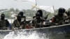 FILE - Militants with Kalashnikov assault rifles and rocket-propelled grenade launchers patrol creeks of the Niger Delta, southern Nigeria, Feb. 24, 2006.
