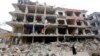 A woman walks past a damaged building in the Douma neighborhood of Damascus, Syria, Feb. 12, 2015.