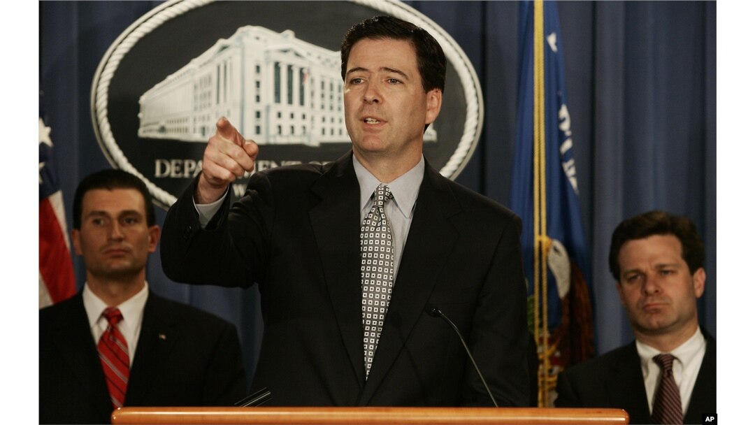 FILE - Deputy Attorney General James B. Comey, center, gestures during a news conference at the Department of Justice in Washington, April 12, 2005. Behind Comey are prosecutor George Z. Toscas, left, and Assistant Attorney General Christopher Wray.