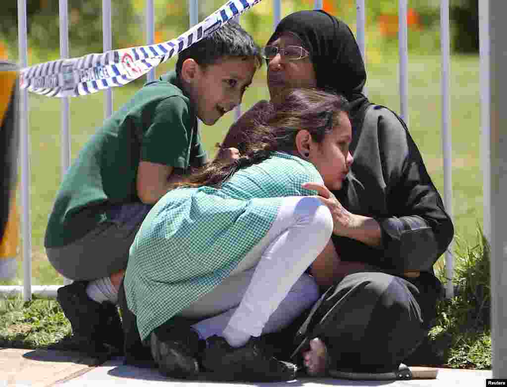 A woman hugs her children where a vehicle crashed into a primary school classroom in the Sydney suburb of Greenacre in Australia.
