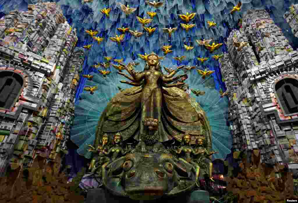 An electrician hangs decorative lights on an idol of the Hindu goddess Durga at a pandal, or a temporary platform, for the upcoming festival of Durga Puja in Kolkata, India.