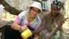 FILE - Sara Laskowski, left, gets a cooking lesson from her Peace Corps "host mother" in Dubreka, Guinea. (Photo courtesy of Sara Laskowski)
