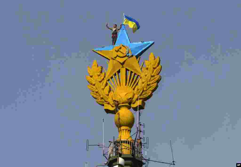 A worker takes a selfie before removing a yellow and blue Ukrainian flag attached by protesters atop Stalin-era skyscraper in Moscow, Russia. Protesters scaled one of Moscow&#39;s famed Stalin-era skyscrapers and painted the Soviet star on its spire in the national colors of Ukraine.